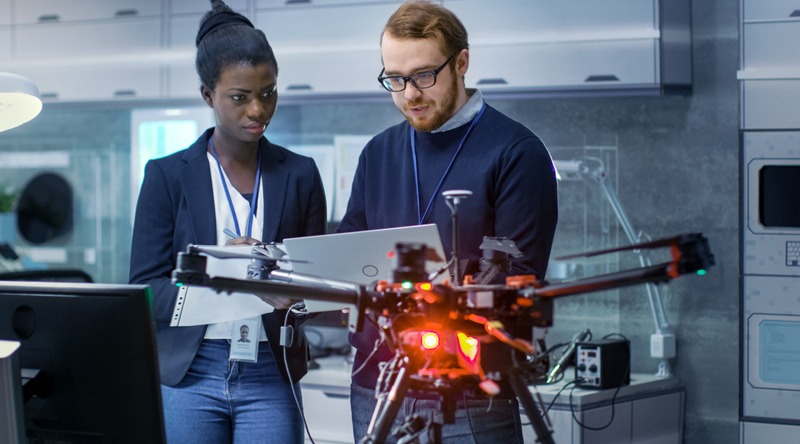 Caucasian Male and Black Female Engineers Working on a Drone Project