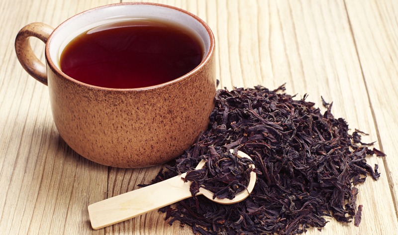 black tea in a cup with dried tea leaves