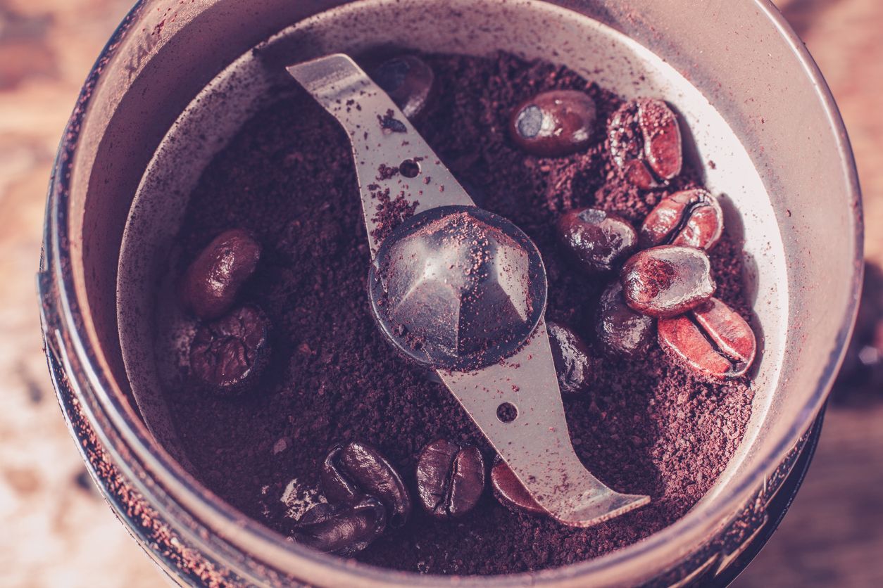 close up on an electric coffee grinder with beans and ground coffee