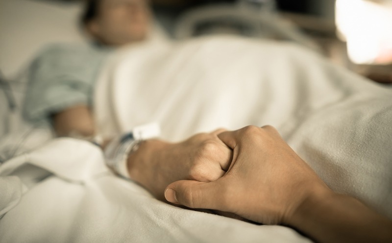 A patient holding hand on a hospital bed