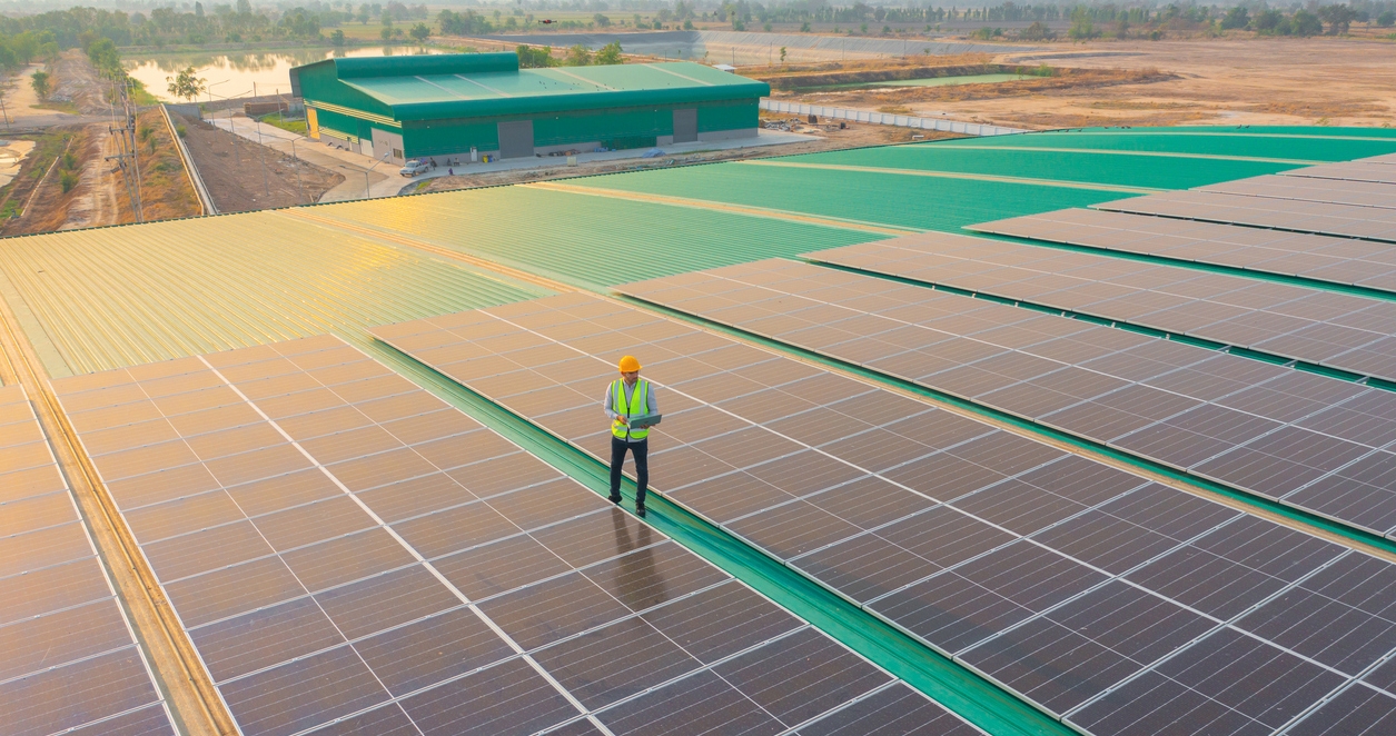 Aerial top view of engineer man or worker,people, with solar panels or solar cells on the roof in factory industry