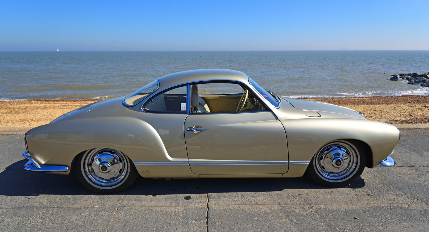 Classic Gold Volkswagen Karmann Ghia parked on seafront promenade