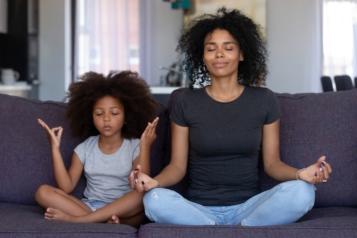 Mindful african mom with funny kid daughter doing yoga