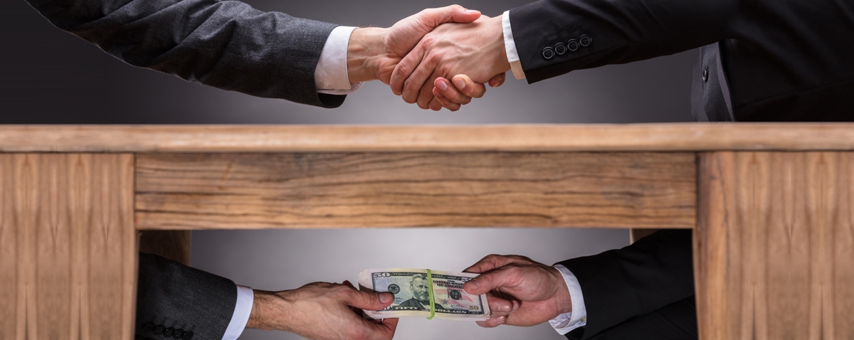 businessmen shaking hands and taking a bribe under the table