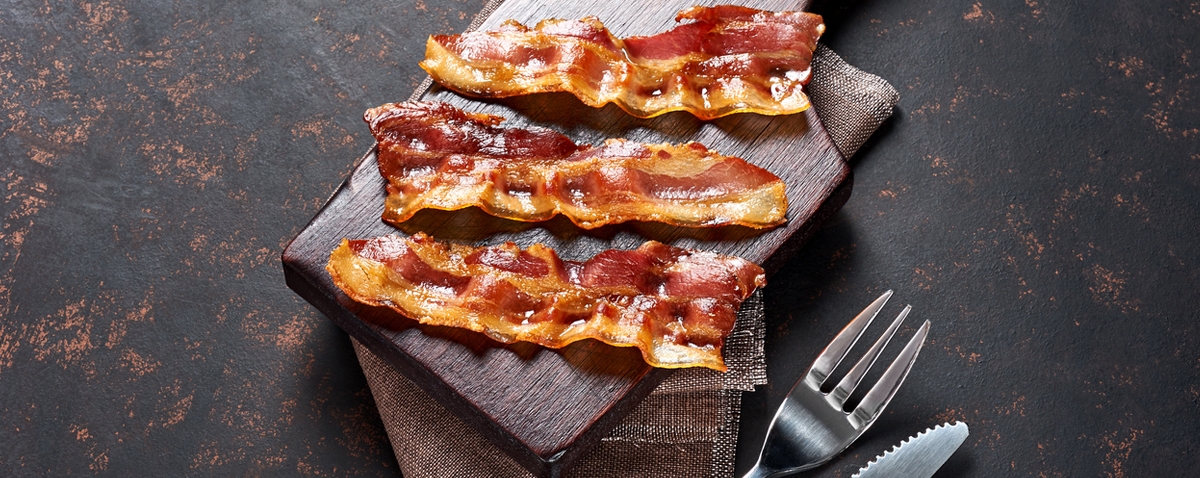 fried bacon on a wooden cutting board