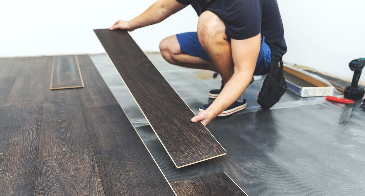 person installing dark brown laminate flooring