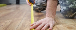 a person measuring the floor using a tape measure