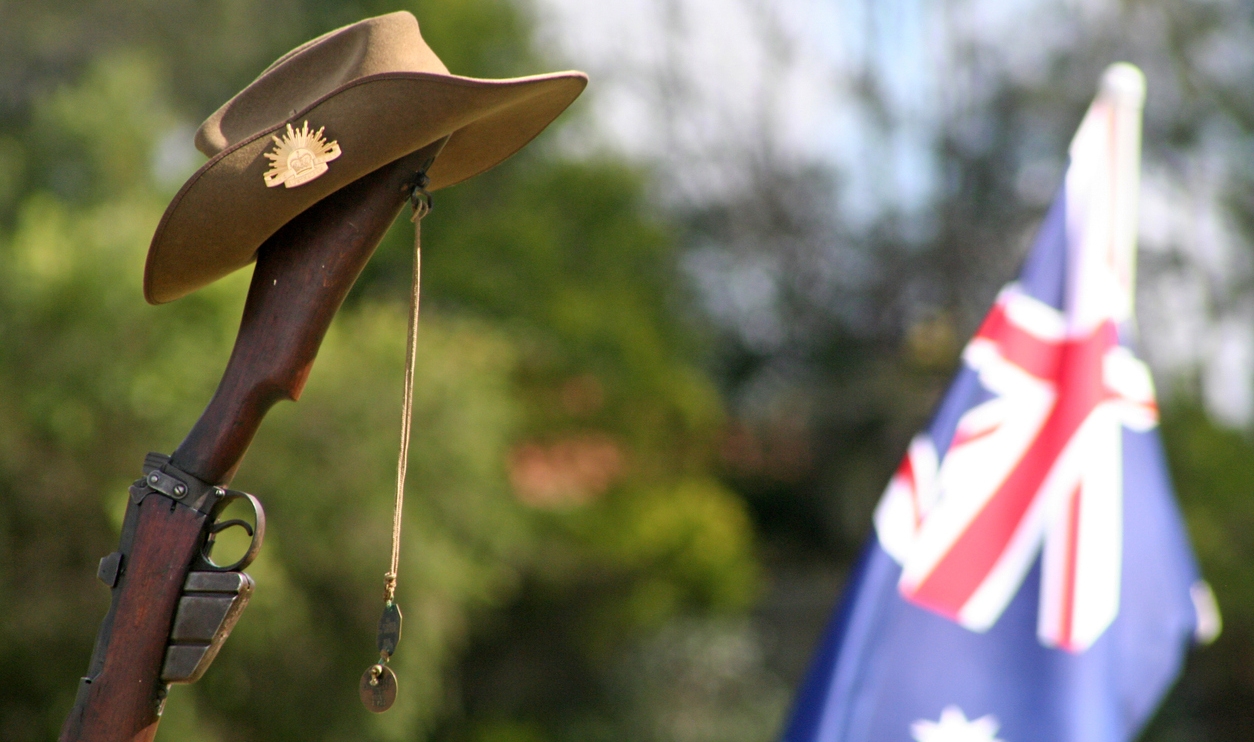 an upturned, vintage Australian Army 303 rifle with the Australian National Flag in the background