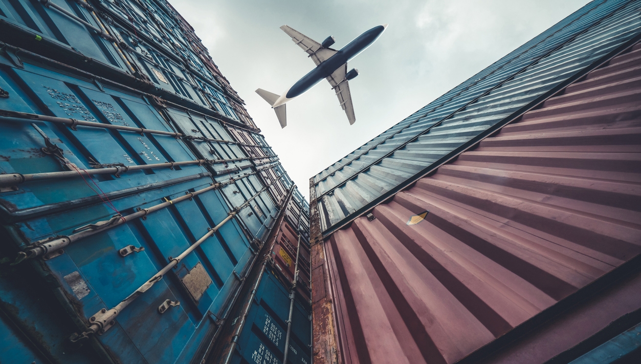 freight airplane flying above overseas shipping container