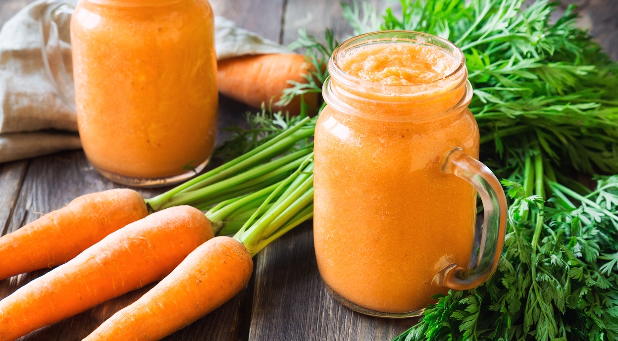 fresh carrots and glasses of carrot smoothies