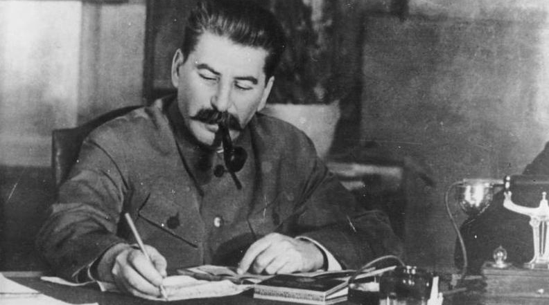 Joseph Stalin signing something on his desk
