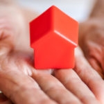 elderly woman holding a small toy house