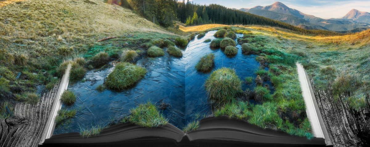 Alpine mountain valley in a light of sunrise on the pages of an open magical book