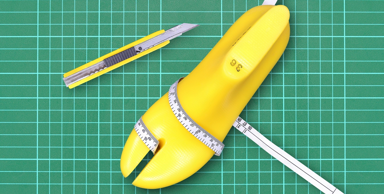 Yellow plastic last shoe, yellow box cutter and measuring tape on rubber cutting mat