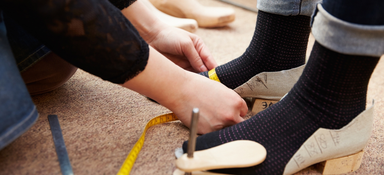 a shoemaker measuring customer’s feet