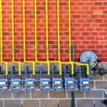 row of natural gas pipes and meters on the wall