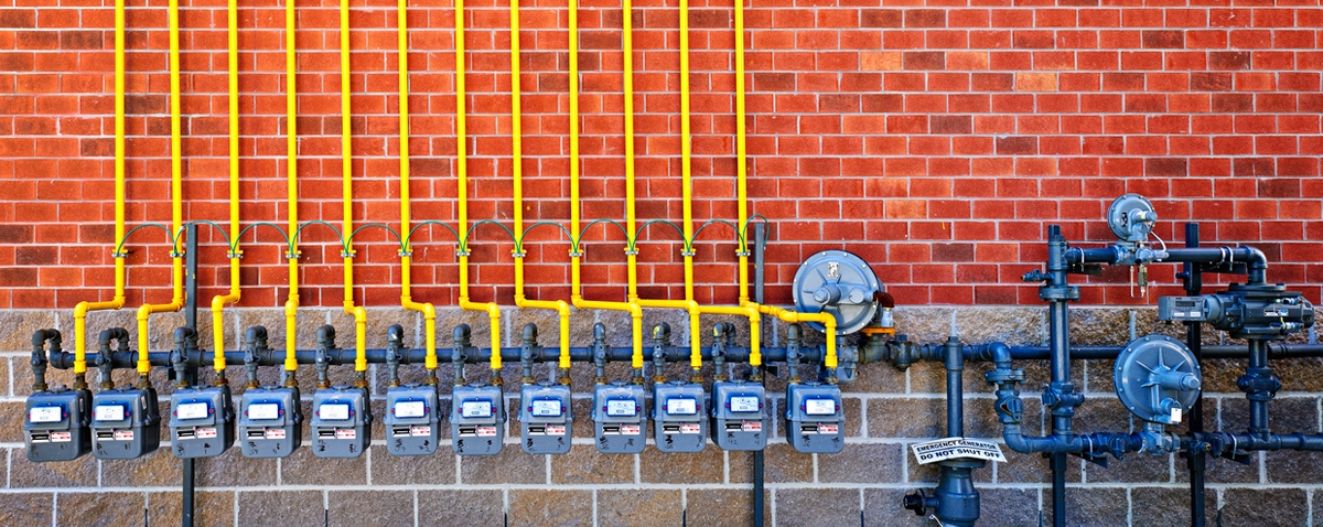 row of natural gas pipes and meters on the wall