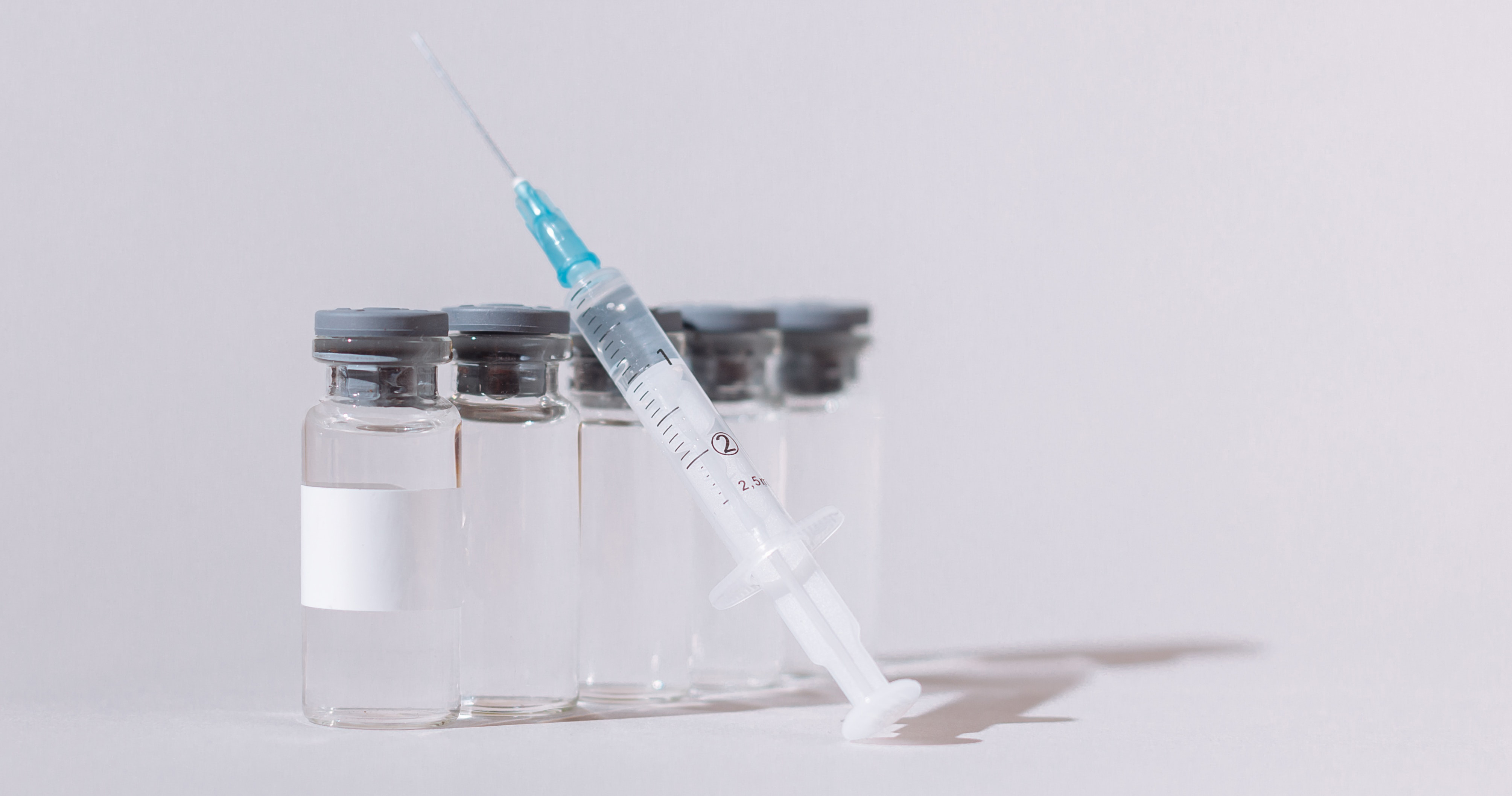 a syringe and several vaccine bottles