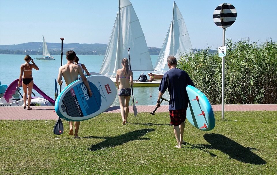 people carrying paddleboards