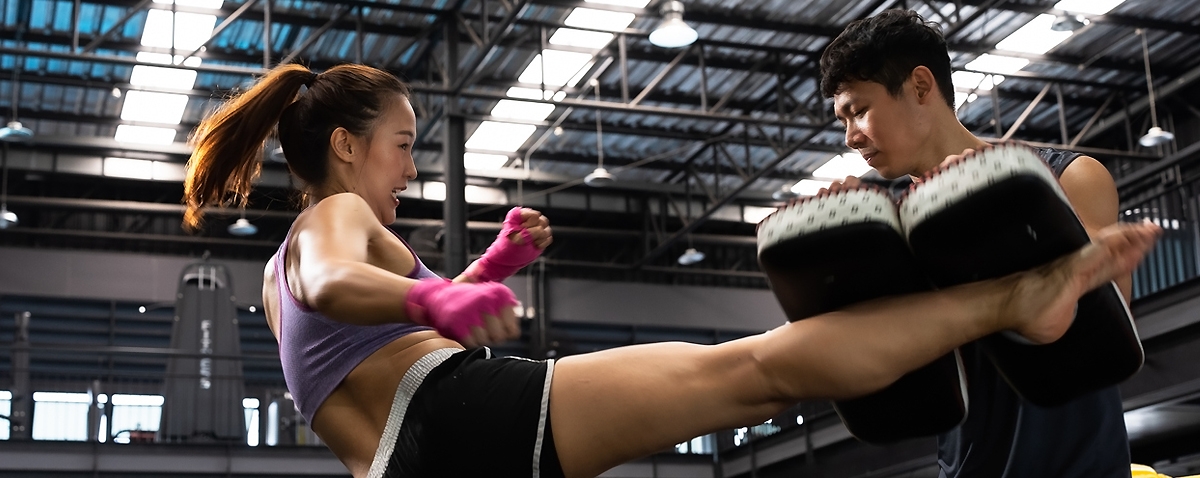 Man giving training to  the woman for Muay Thai