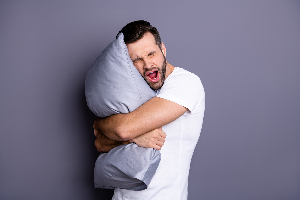 guy yawning while holding a pillow